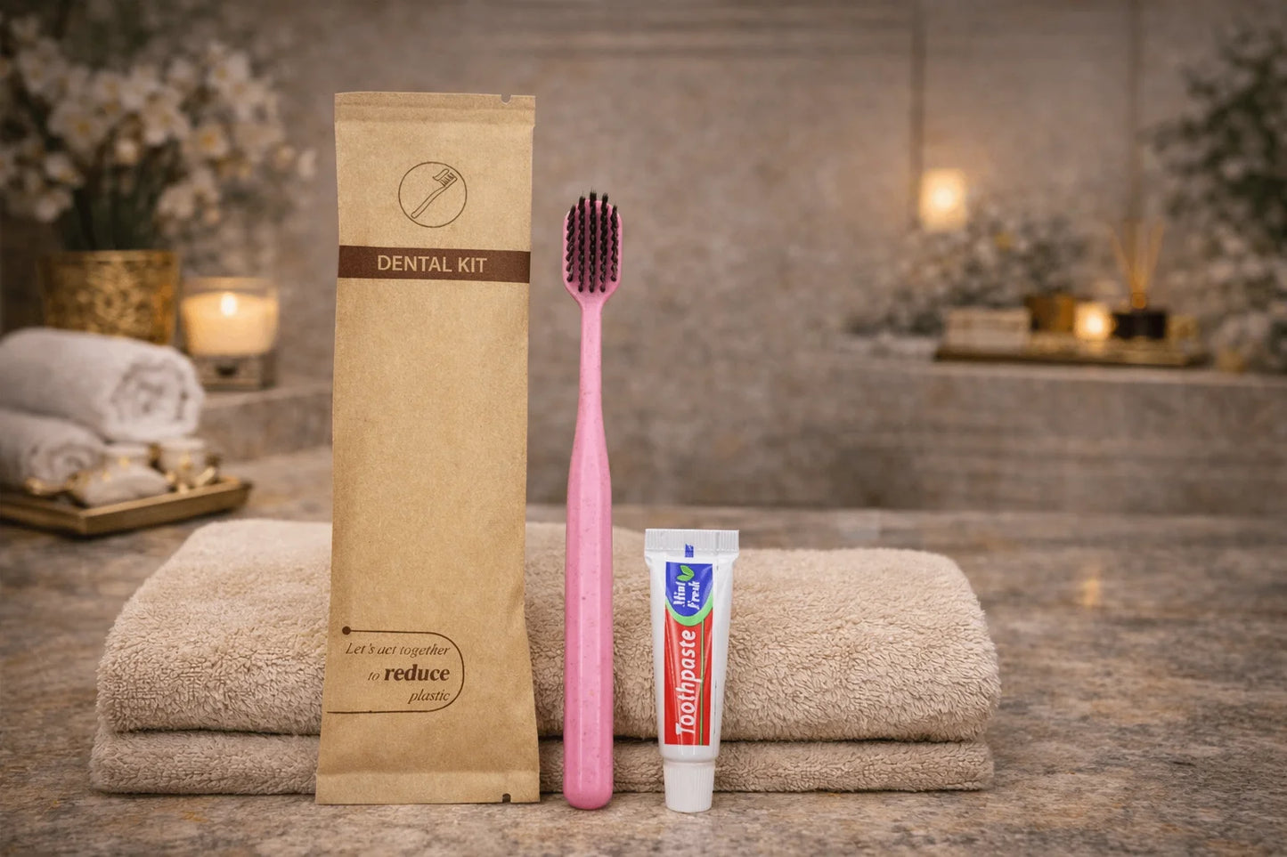 Dental kit with toothbrush, toothpaste, and packaging on a towel in a bathroom setting.