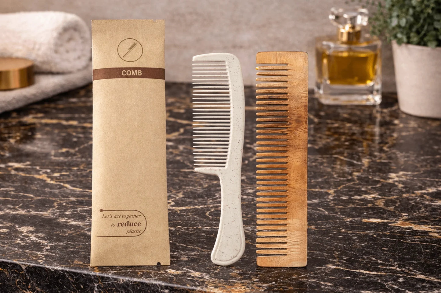 Two combs and their packaging on a marble surface with a glass of water and plant in the background.