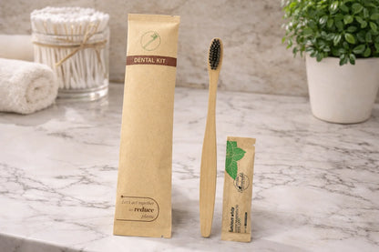 Dental kit with bamboo toothbrush and packaging on a marble surface.