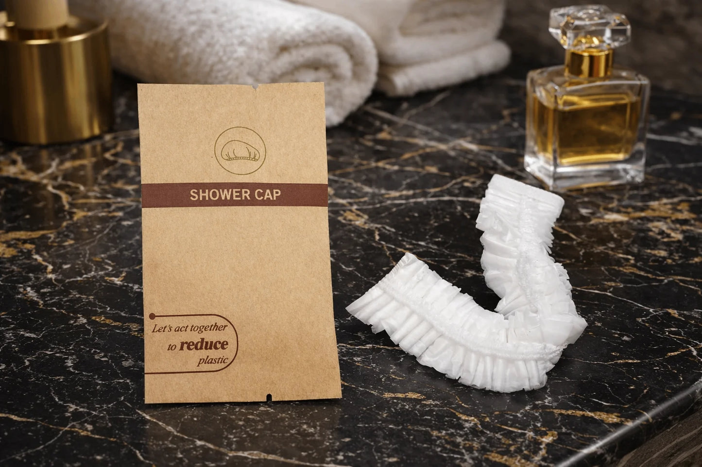 Shower cap packaging on a marble surface with a shower cap and perfume bottle.