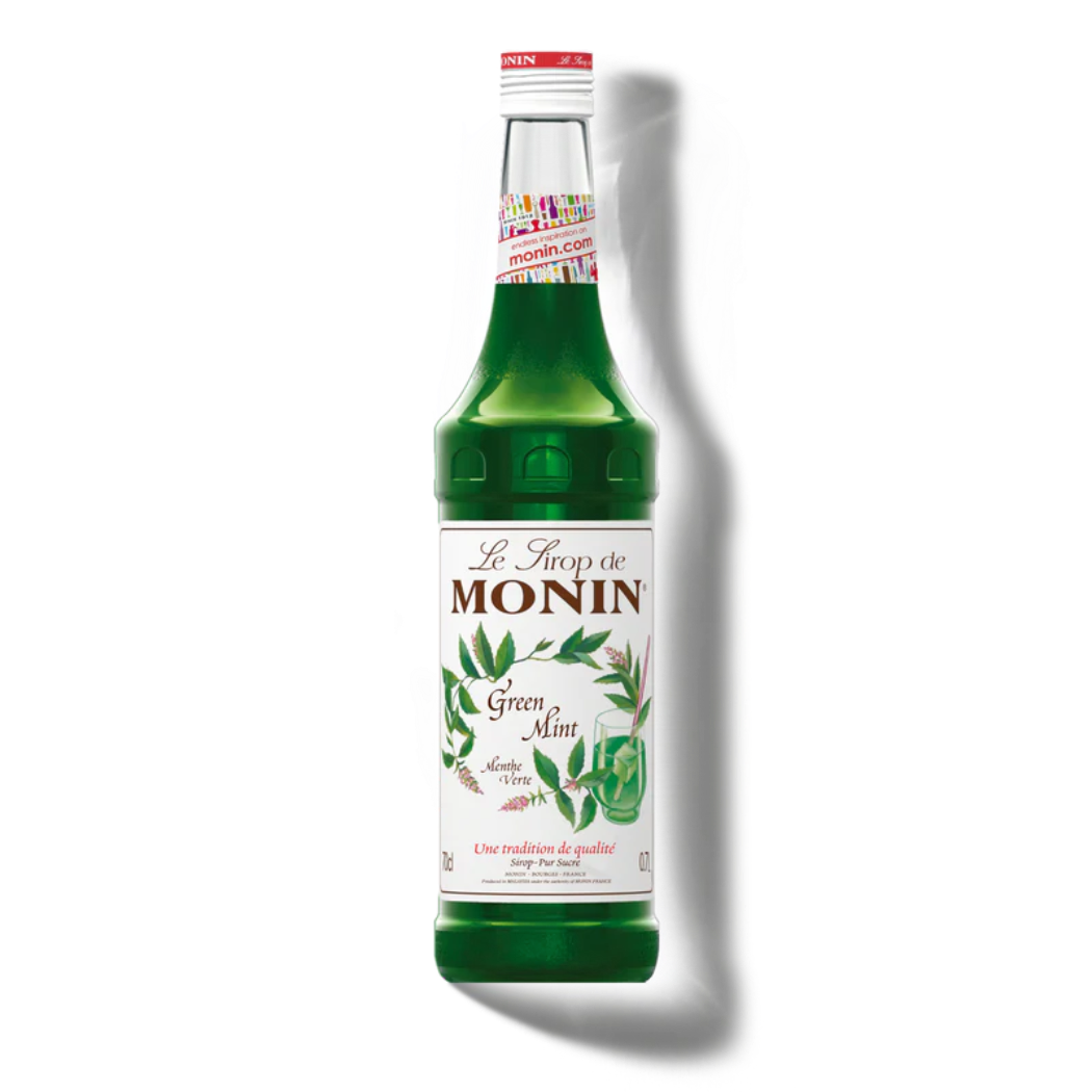 Green bottle of Monin syrup with a white label on a white background