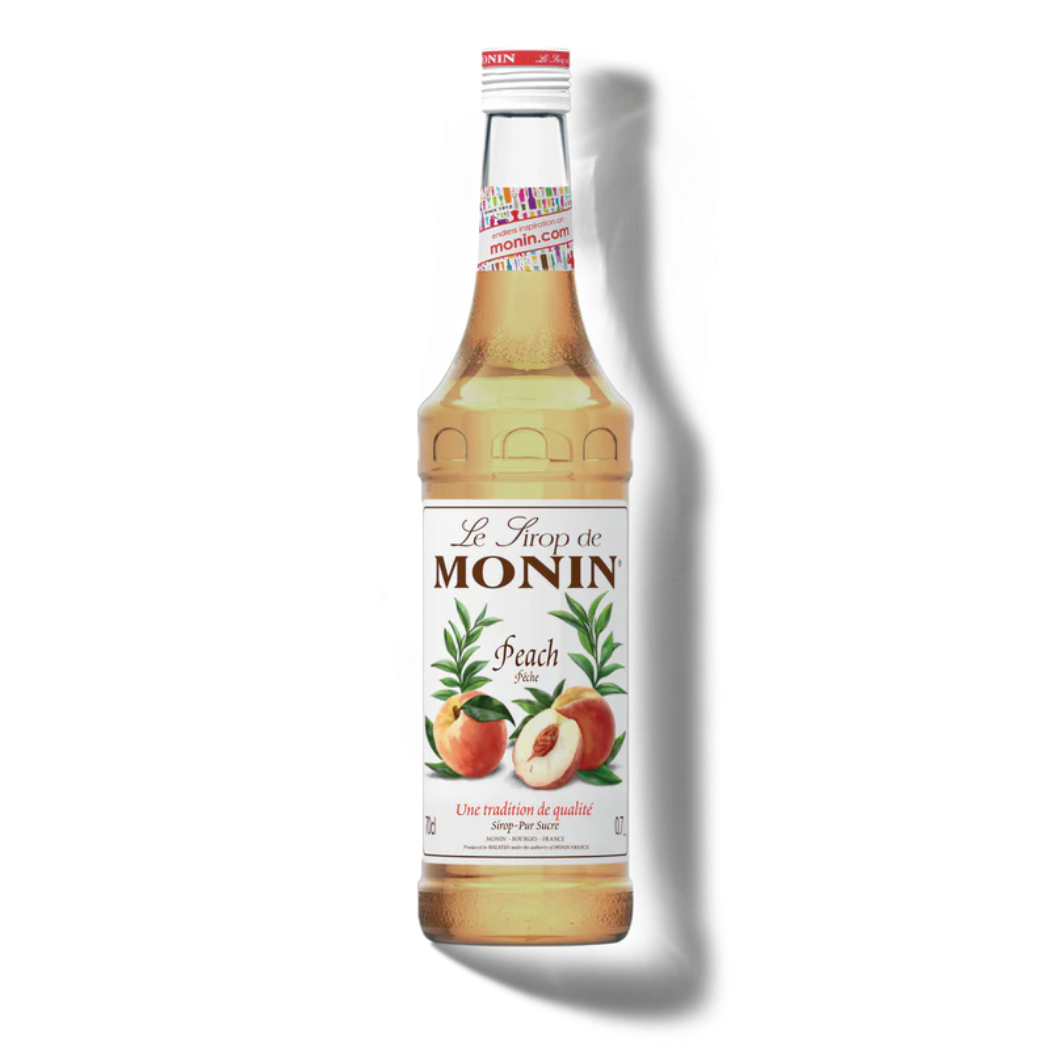 Monin peach syrup bottle on a white background