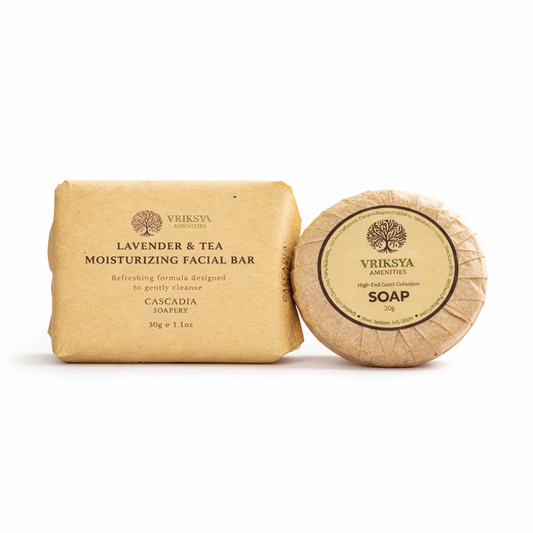 Two soap bars with 'Vriksha' branding on a woven mat with lavender and tea leaves.